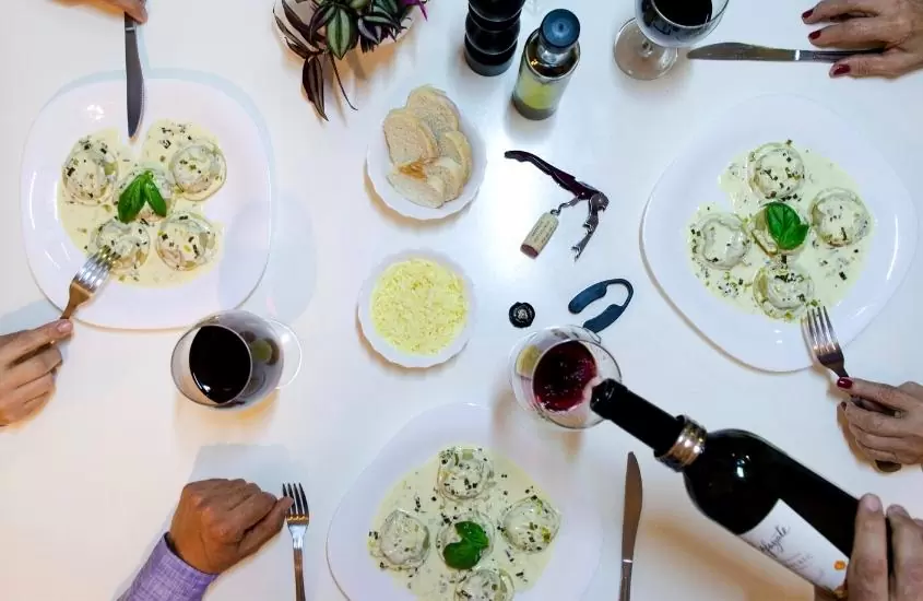 vista de cima de pratos com massas e taças de vinho em cima de mesa branca