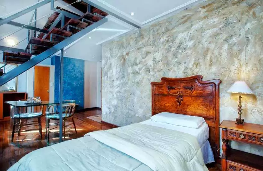 Quarto de um dos melhores hotéis em Buenos Aires com cama de solteiro, mesa, cadeiras, cômoda, cadeiras e escadas