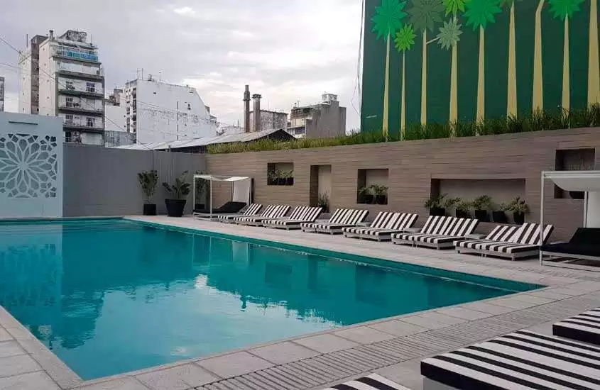 Em um dia nublado, área de lazer na cobertura de hotel em Buenos Aires com piscina, espreguiçadeiras e plantas ao redor