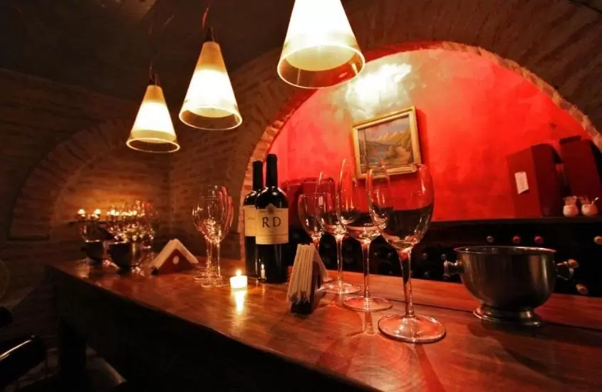taças de vidro e garranhas de vinho em cima de mesa de madeira em bar de Miravida Soho Hotel & Wine Bar, um dos hotéis em buenos aires 5 estrelas