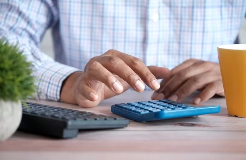 pessoa usando calculadora azul em cima de mesa da madeira