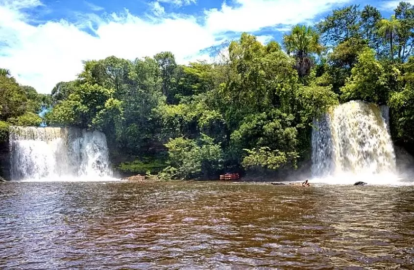 quedas d'água de cachoeiras cercadas de árvores, em frente a rio, durante o dia em cachoeiras gêmeas do itapecuru, um dos passeios na chapada das mesas