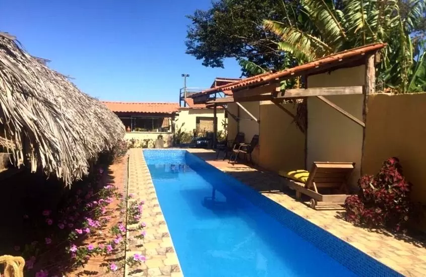 espreguiçadeiras em frente a piscina, durante o dia em Hospedagem Portal da Terra