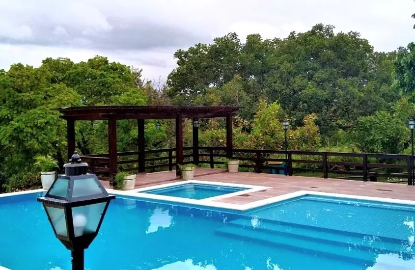 piscina cercada de árvores, durante o dia em área de lazer de Pousada Portalcion