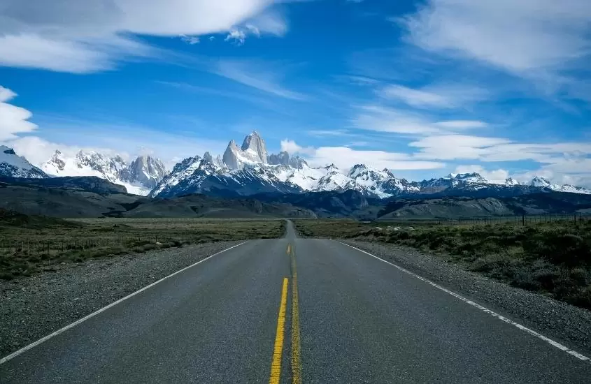 estrada sem carros e ao fundo montanhas cobertas de neve, durante o dia em um dos melhores destinos na argentina