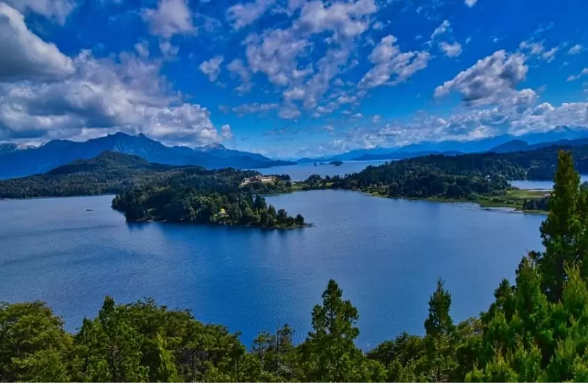 vista aérea de lago cercado por árvores, durante o dia em bariloche, um dos melhores destinos na argentina
