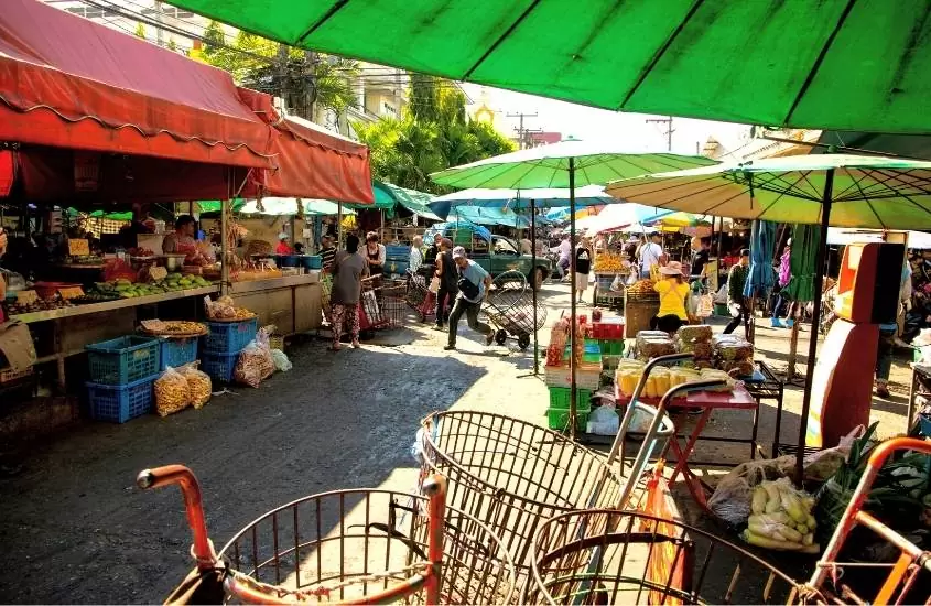 durante o dia, pessoas caminhando entre barracas de comidas, em um dos mercados em chiang mai, ao ar livre