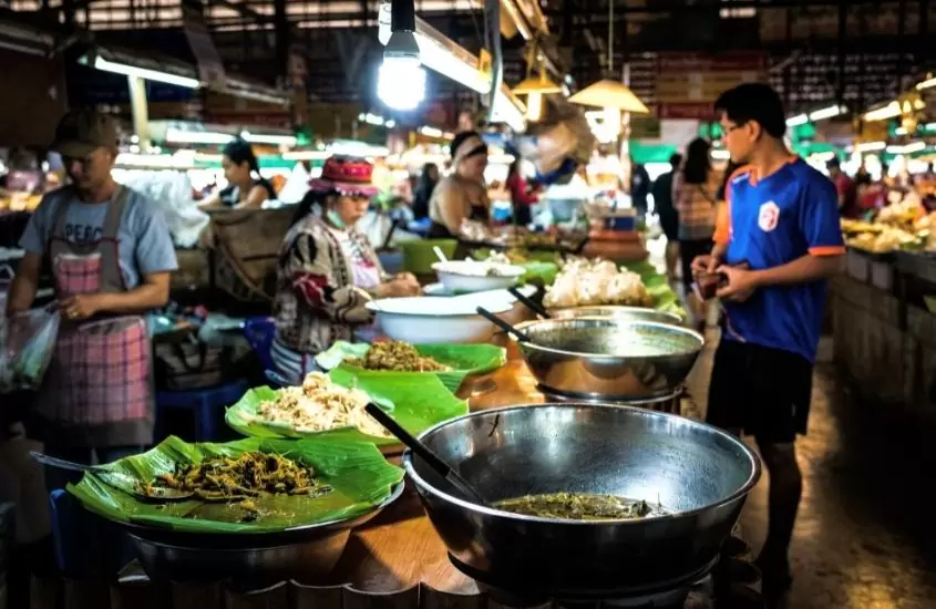 homem comprando comida tailendesa em barraca de um dos mercados em chiang mai