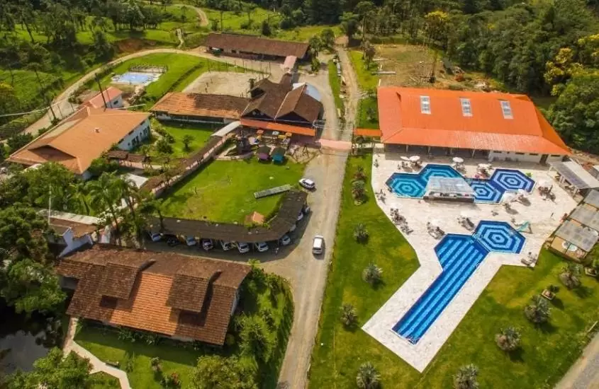 durante o dia, vista aerea de casas e piscinas, cercadas de árvores em hotel fazenda dona francisca