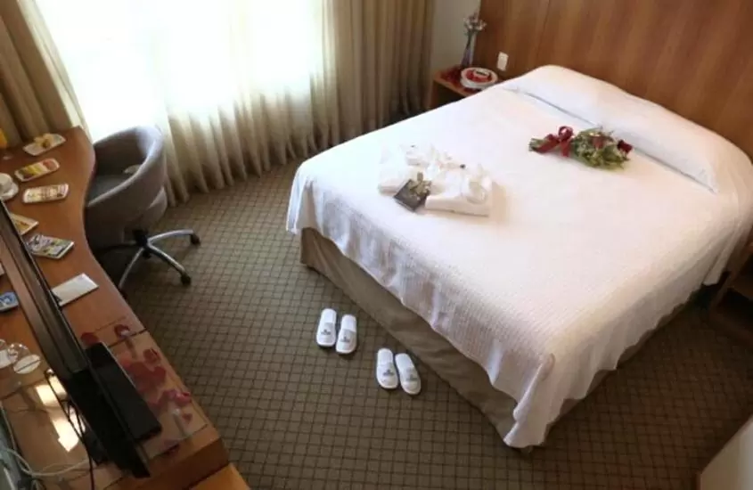 buquê de flores em cima de cama de casal em frente a televisão, em quarto de Bourbon Joinville Convention Hotel