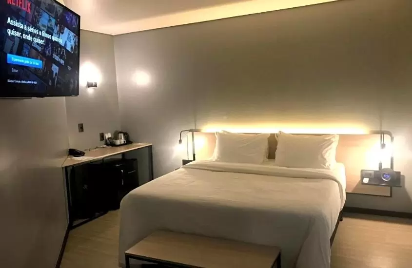 televisão exibindo netflix em frente a cama de casal em suíte de Naalt Hotel Joinville
