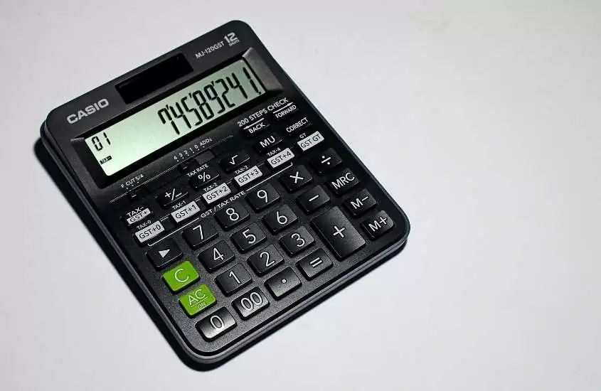 calculadora preta em cima de mesa branca para calcular o preço de uma viagem para joinville