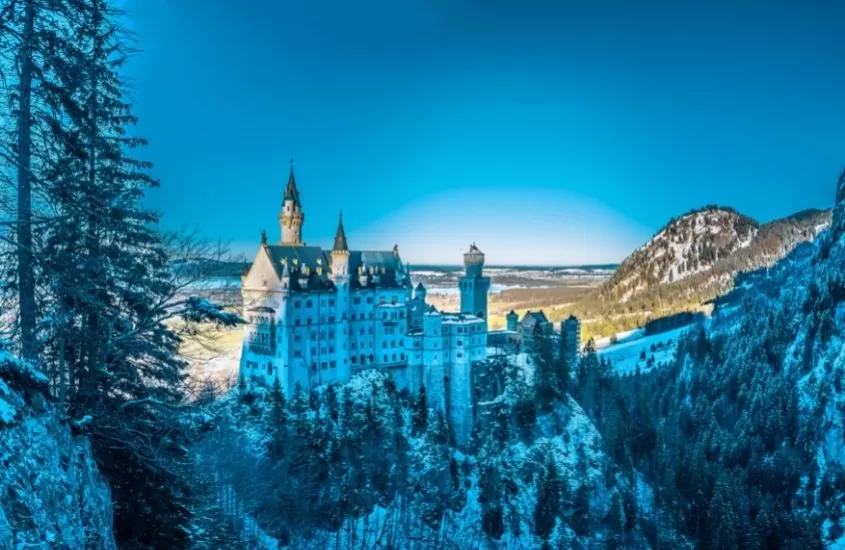 castelo em montanha coberta de neve, durante o dia em alemanha no inverno