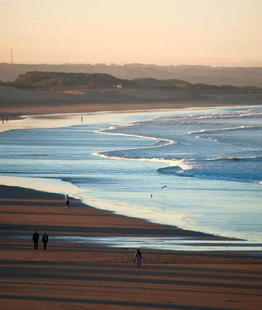 durante o dia, vista aérea de pessoas caminhando em areia de praia em agadir, destino para um roteiro marrocos