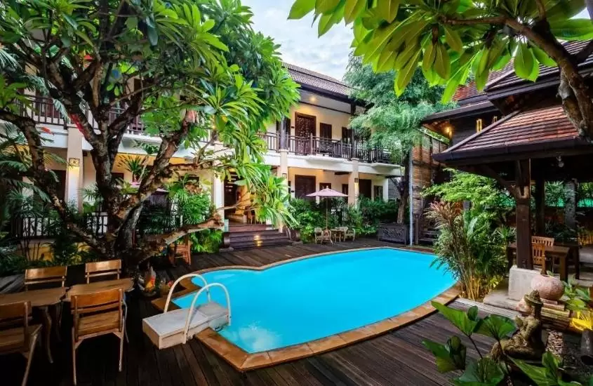 durante o dia, piscina cercada de árvores em um dos melhores hotéis em chiang mai para famílias