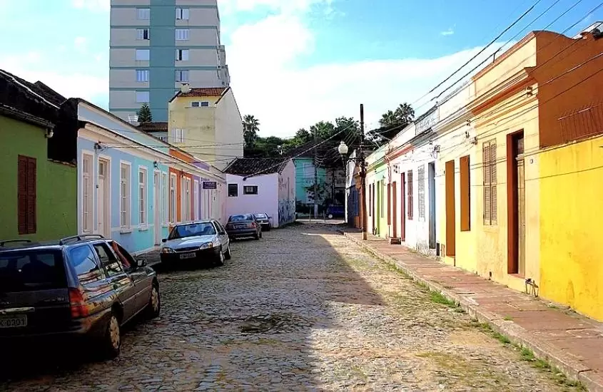 durante o dia, carros estacionados em rua cheia de casas coloridas em cidade baixa, lugar onde ficar em porto alegre rs