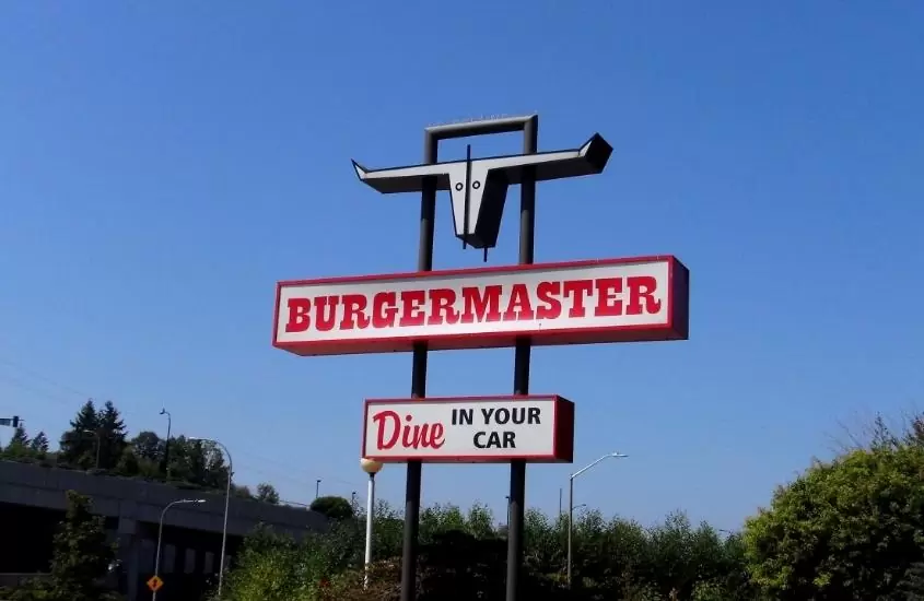 durante o dia, letreiro branco e vermelho onde há escrito 'burgermaster, dine in your car'
