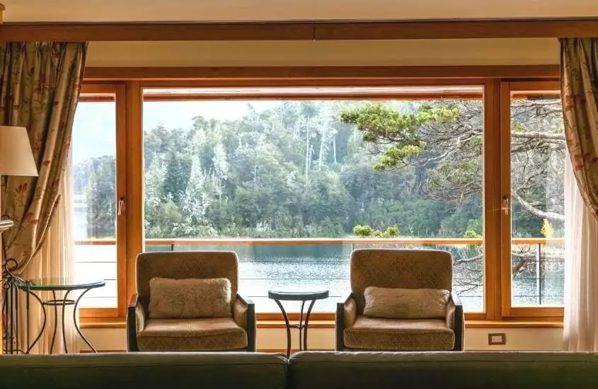durante o dia, duas poltronas em suite com ampla janela com vista para o lago