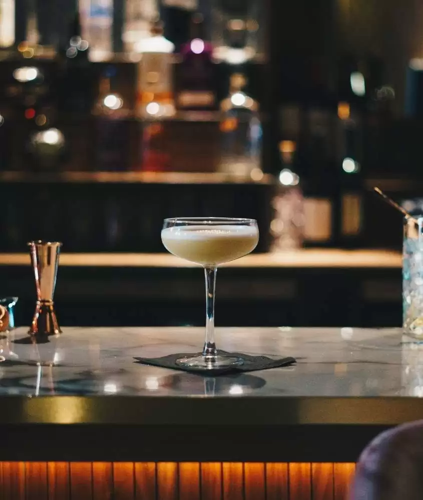taça de vidro com drink, em cima de balcão de bar, lugar para quem busca o que fazer a noite em san diego