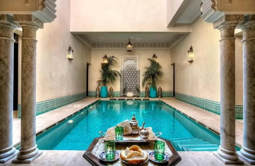 chá e salgados servidos em bandeja à beira de piscina coberta de um dos riads em marrakech