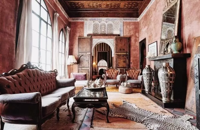 poltronas, sofás, abajures e mesas em sala de estar laranja de suíte de um dos melhores riads em marrakech