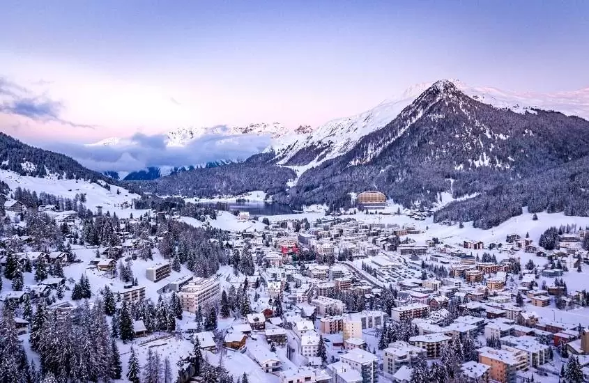 durante o dia, vista aérea de casas e montanhas cobertas de neve em davos, uma das cidades suíças famosas