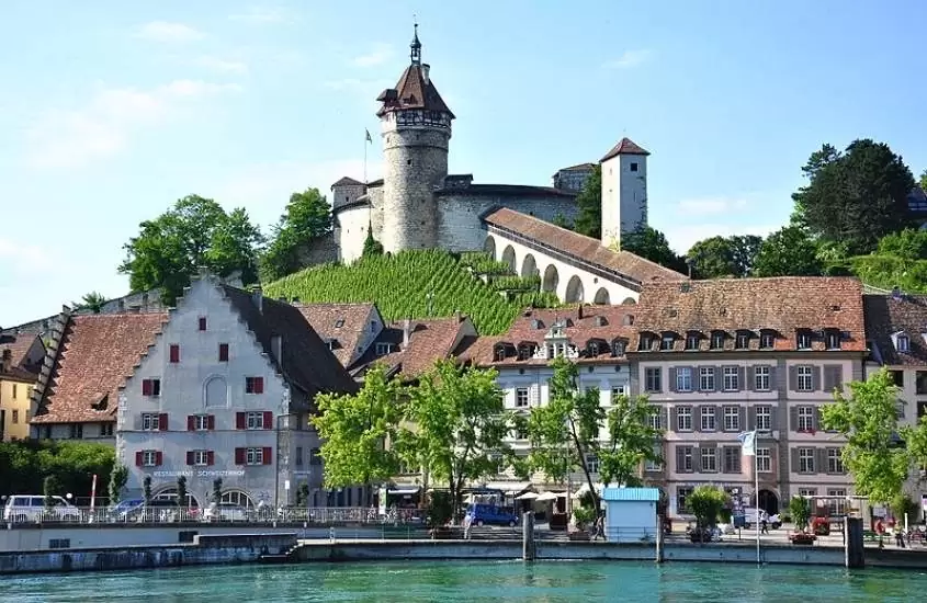 durante o dia, castelo e casas em frente a lago em Schaffhausen, uma das cidades suíças