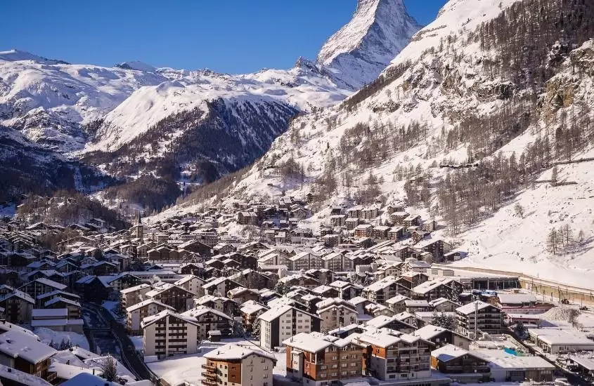durante o dia, casas em frente a montanhas nevadas em Zermatt, uma das melhores cidades na suíça no inverno