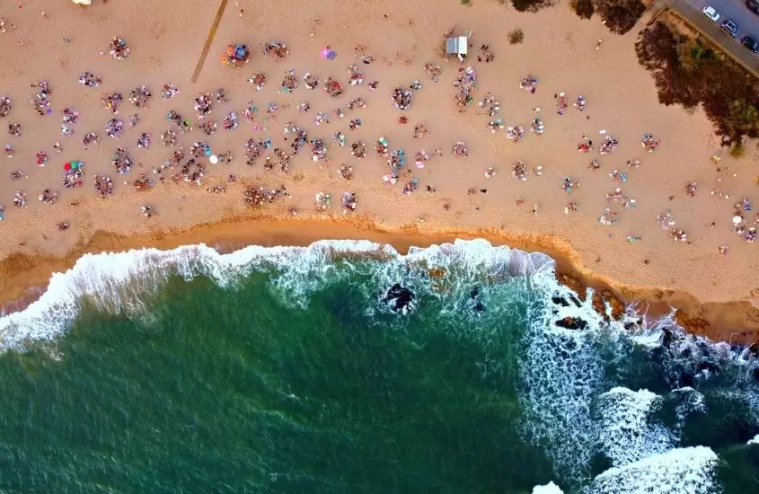 durante o dia, vista aérea de guarda-sóis coloridos em areia em frente ao mar