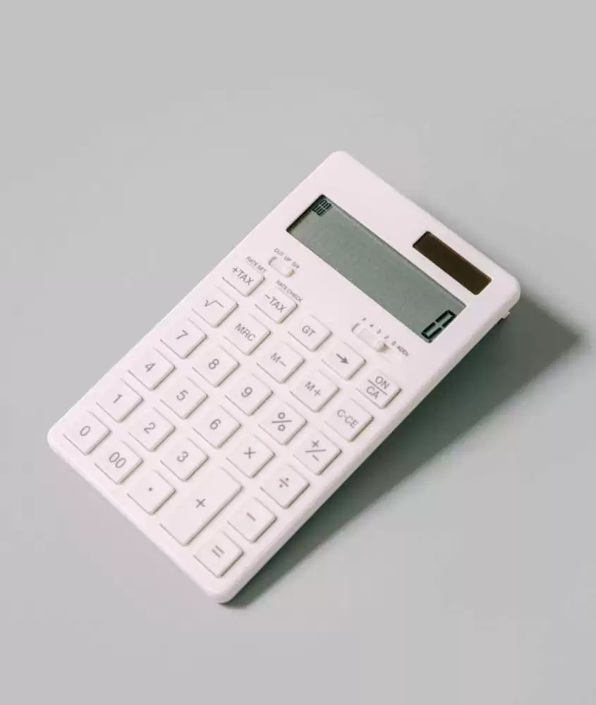 calculadora branca em cima de mesa cinza para calcular custos de viagem para Punta del Este