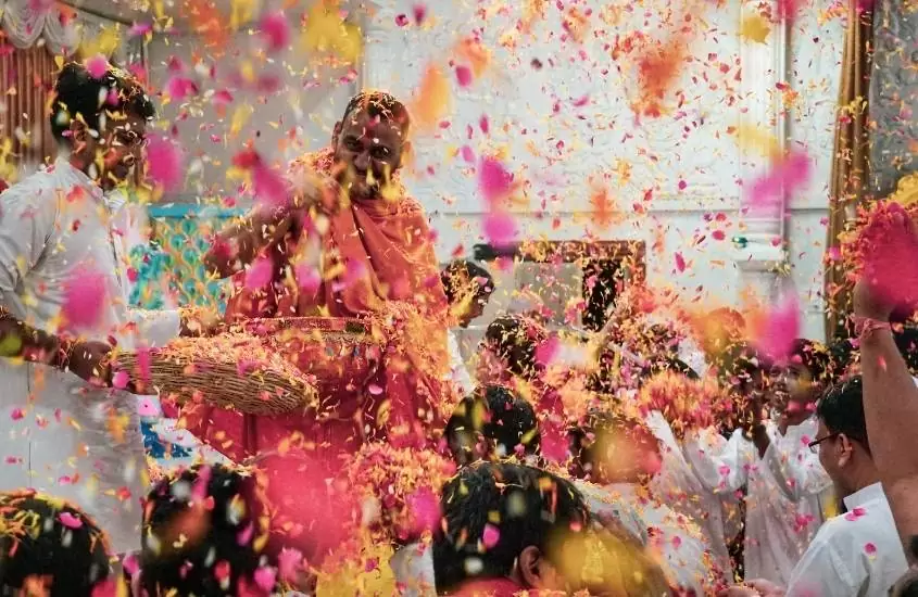 durante o dia, pessoas jogando pó colorido umas nas outras, durante festival holi