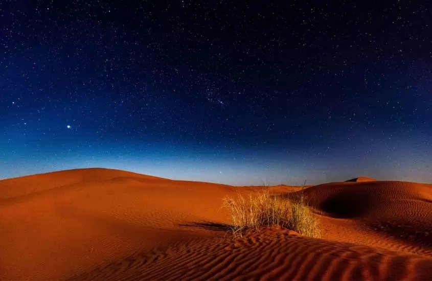 durante a noite, dunas de areia no deserto sob céu estrelado