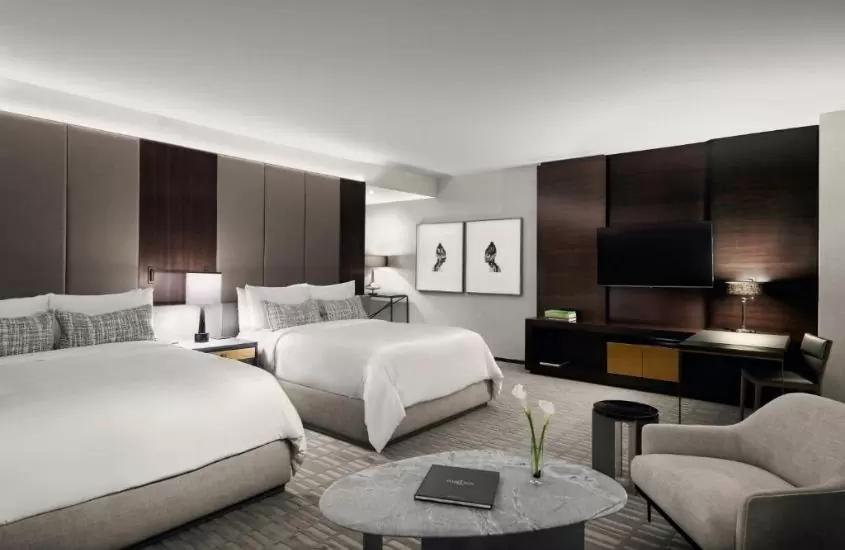 duas camas de casal, mesa redonda e poltrona em suíte de um dos melhores hotéis em Toronto