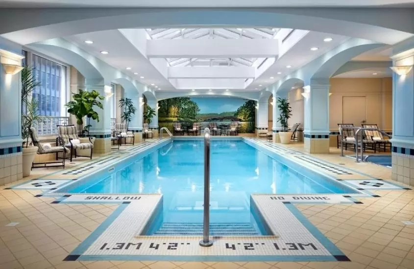 poltronas em frente a grande piscina em área de lazer coberta em um hotel em toronto