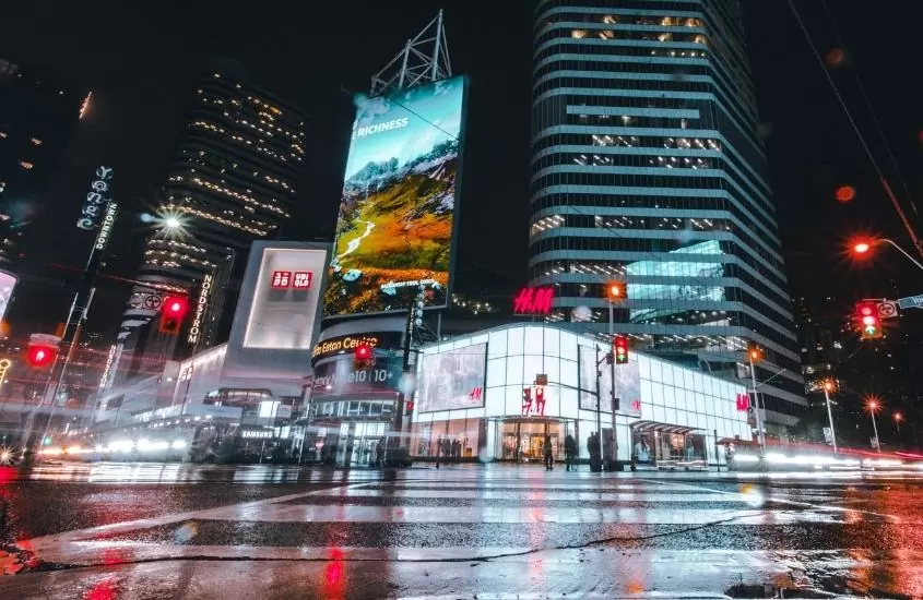 durante a noite, prédios com painéis iluminados em ruas de yonge-dundas, lugar onde se hospedar em Toronto