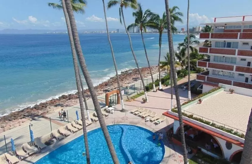 durante o dia, vista aérea de espreguiçadeiras ao redor de piscina em área de lazer com vista para o litoral do México
