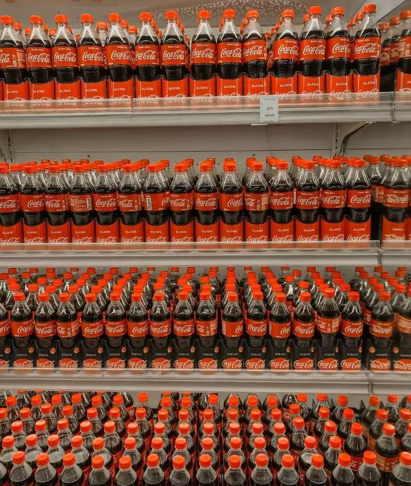 diversas garrafas de coca-cola em prateleira de mercado