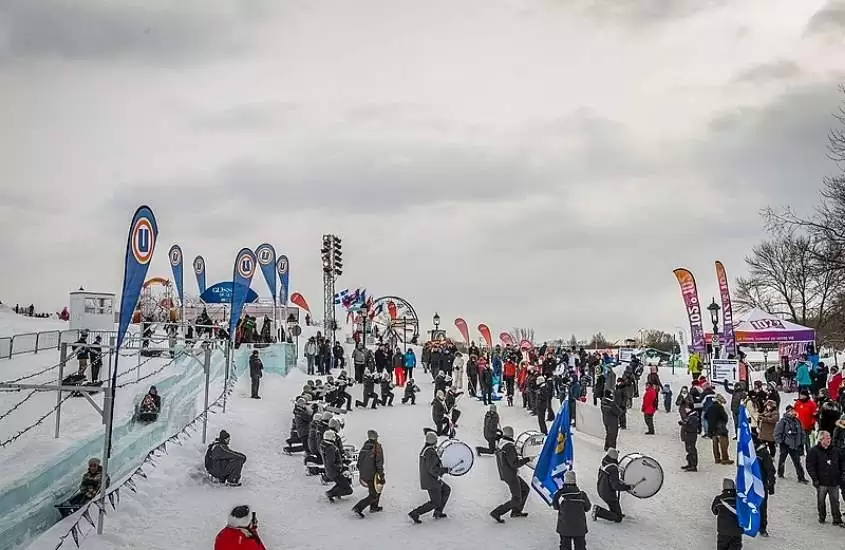 durante o dia, pessoas tocando tambores em desfile de carnaval de inverno em quebec