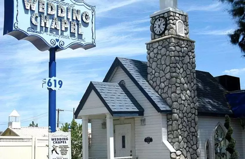 durante o dia, placa azul onde há escrito ''wedding chapel'' em frente a casa branca com telhado azul