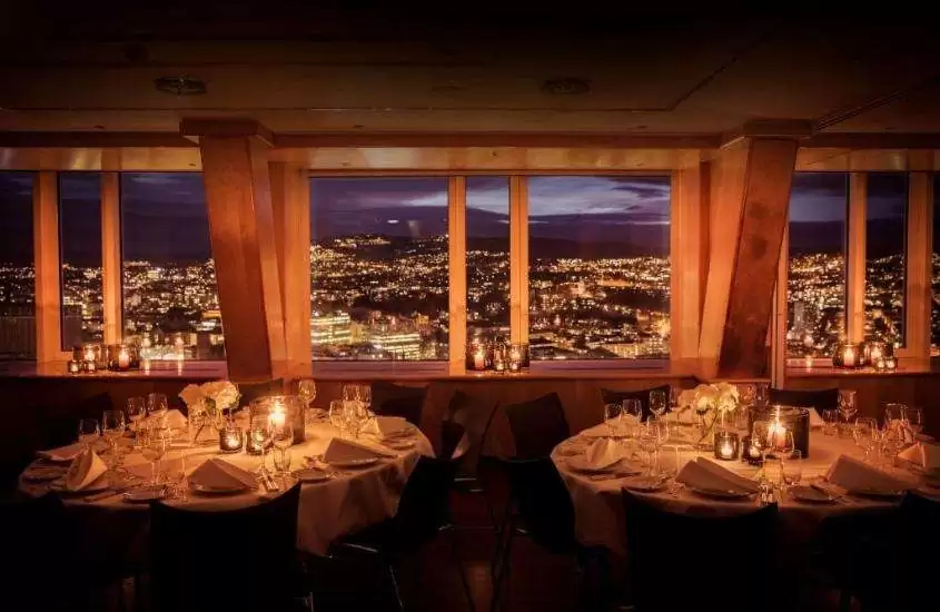 durante a noite, cadeiras ao redor de mesas redondas em restaurante com vista para a cidade