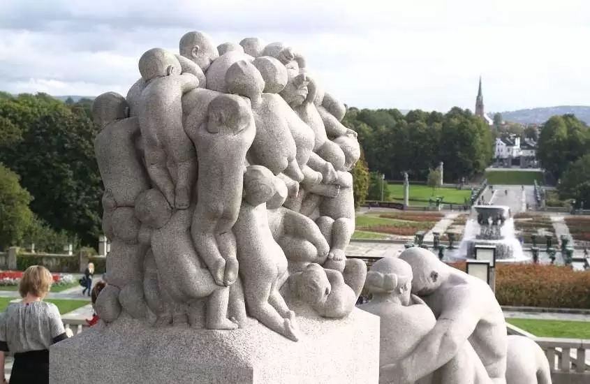durante o dia, esculturas de pessoas grudadas umas nas outras em gramado de parque