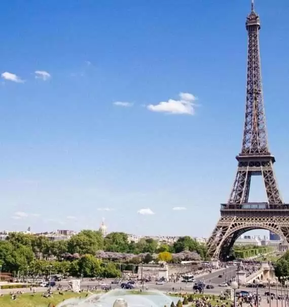 durante o dia, pessoas caminhando em gramado com vista para a Torre Eiffel, torre de treliça de ferro