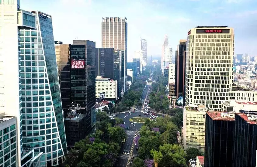 durante o dia, vista aérea de prédios em frente a avenida arborizada em Reforma, bairro onde ficar na cidade do méxico pela primeira vez