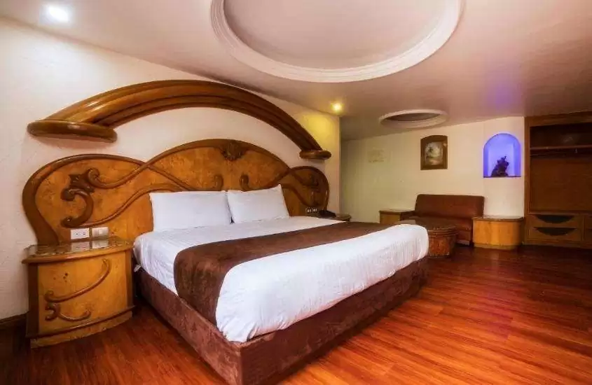 mesa de cabeceira e cama de casal de madeira em suíte de um dos melhores hotéis na cidade do méxico