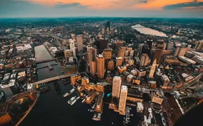 durante entardecer, vista aérea de arranha-céus e prédios em frente ao mar em boston eua