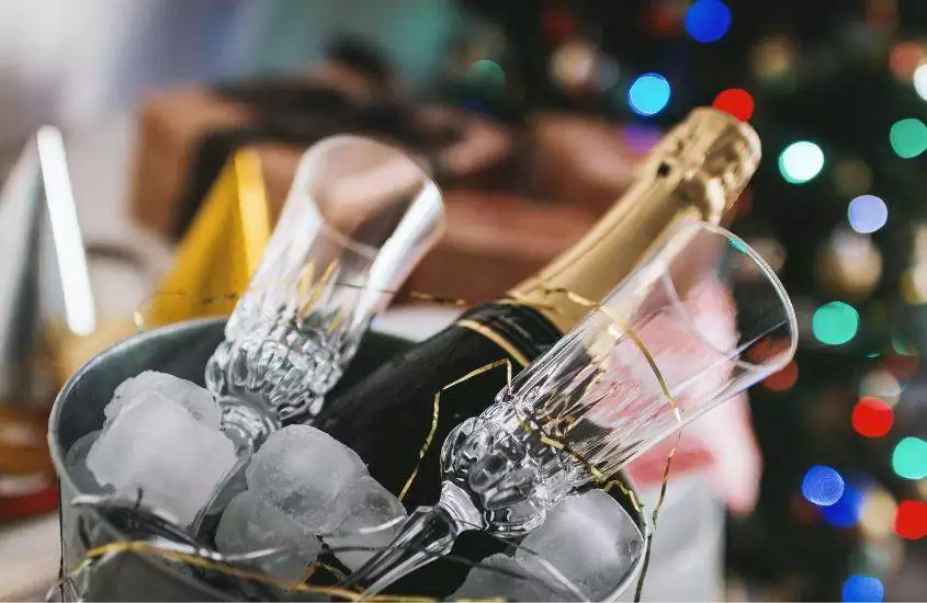 taças de vidro transparentes e garrafa de champagne dentro de balde para comemorar o réveillon Jericoacoara 2024