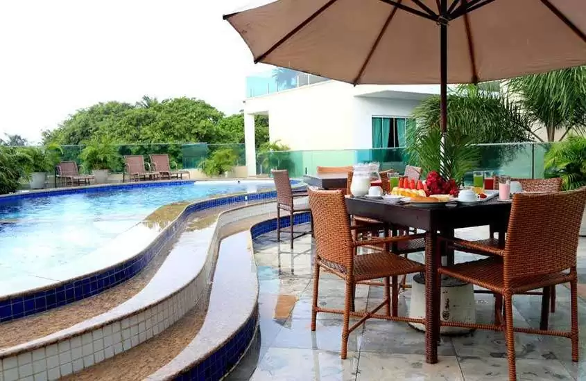 durante dia nublado, mesa de café da manhã servida em frente a piscina ao ar livre de hotel no centro de jeri