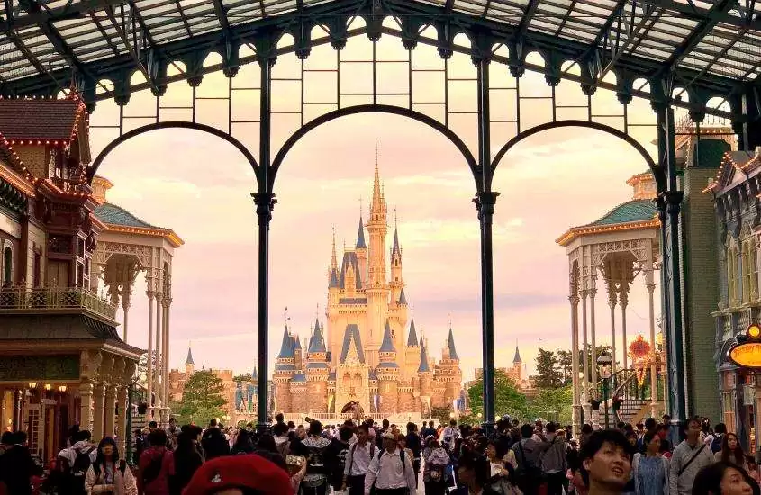 durante o dia, pessoas caminhando em direção a castelo em Disneyland, um dos pontos turísticos de tokyo
