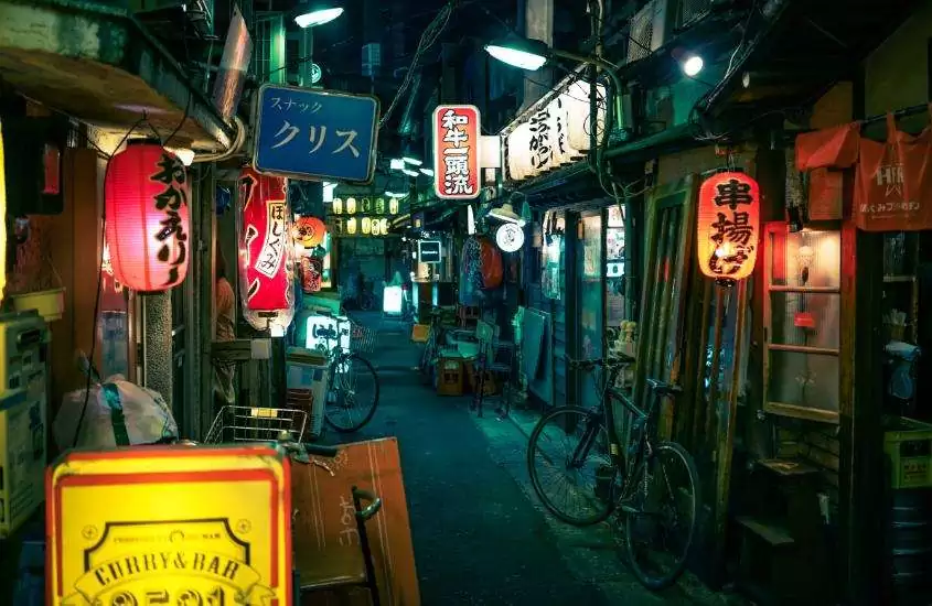 durante a noite, bicicletas estacionadas em porta de bares em beco cheio de restaurantes