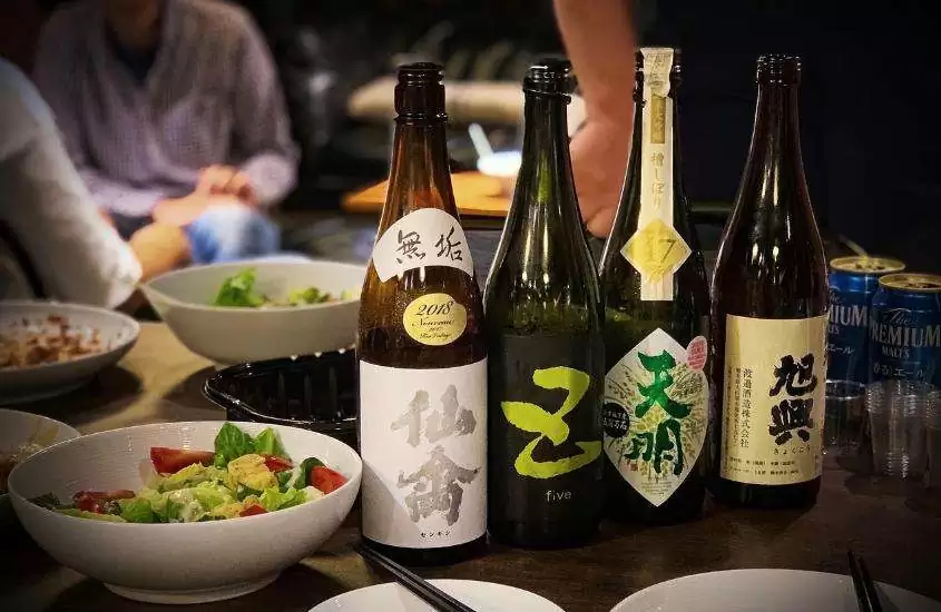 diversas garrafas de saquê em cima de mesa em um dos restaurantes em Tokyo